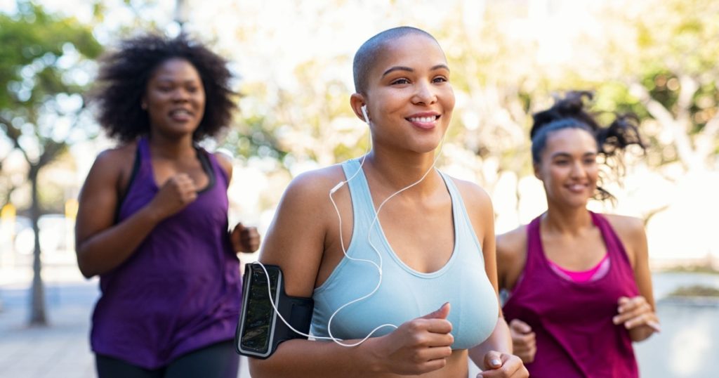 Three women running outdoors on a sunny day.