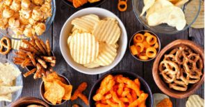 Photo of table full of junk foods, including chips, pretzels, cheesy puffs, caramel corn, and more.