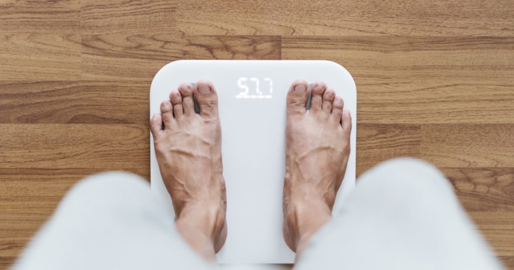 Man standing on white digital scale, from man's point of view.